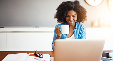 Teacher sitting at laptop with a coffee in hand