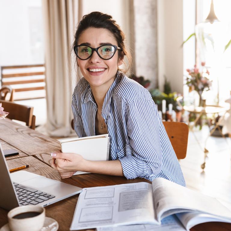 Woman smiling at desk with notebook and laptop