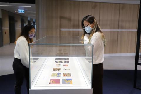 Two students peering into glass case at prints