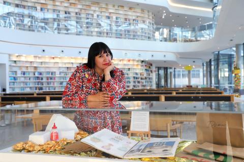 Creative in Residence Raquel Caballero leaning against a glass display filled with her progress diaries