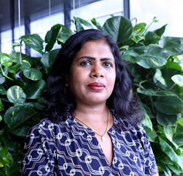 Close-up of Priya standing in front of a leafy background